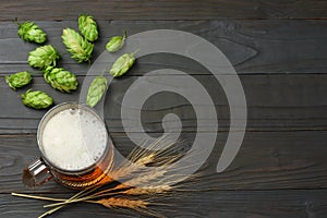 Glass beer with hop cones and wheat ears on dark wooden background. Beer brewery concept. Beer background. top view