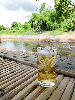 Glass of beer with ice on bamboo table