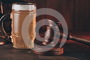 Glass of beer and judge gavel as a symbol of law on a wooden table close-up