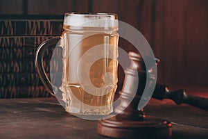 Glass of beer and judge gavel on a wooden table close-up. Alcohol and crimes concept