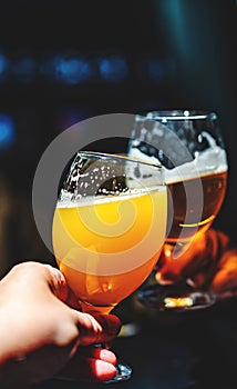 Glass of beer in man hand. Beer glasses clinking in bar or pub