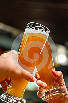 Glass of beer in man hand. Beer glasses clinking in bar or pub