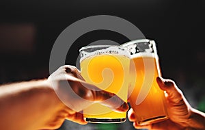 Glass of beer in man hand. Beer glasses clinking in bar or pub