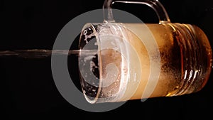 Glass beer mug. Non-alcoholic beer, low key, dark background. Beer pours into the mug with a trickle. vertical video