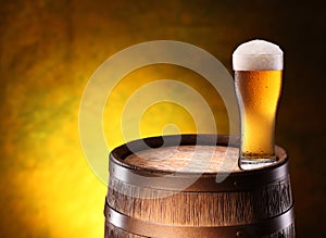 The glass of beer over woden barrel.