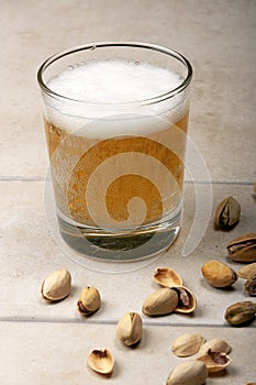 A glass of beer and pistachios