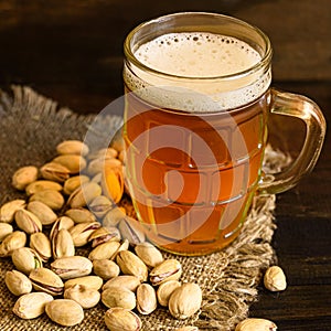 Glass of beer and pistachios at a wooden table