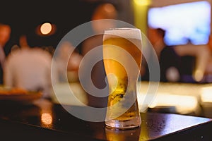 Glass of beer placed casting a shadow on the sky bar counter in restaurant