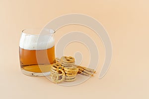 Glass of beer and pretzel on yellow background. Copy space