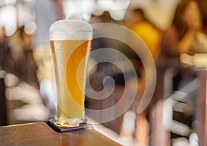 Glass of beer stands on a table in a pub. White unfiltered beer