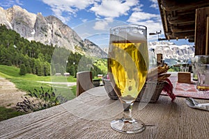 A glass of beer on the table against the background of a beautiful Dolomite landscape