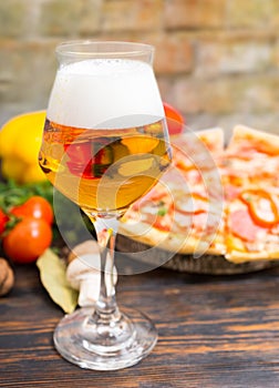 Glass of beer and tasty pizza with salami on background