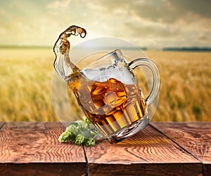 Glass of beer on wooden table with sea on background