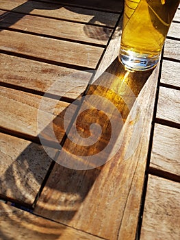 Glass of beer on wooden table with sunlight shining through the drink