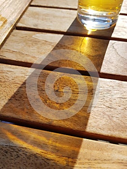 Glass of beer on wooden table with sunlight shining through the drink