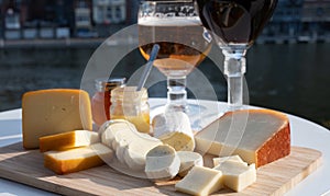 Glass of Belgian abbey beer and tasting of cheeses made with trappist beer and fine herbs with view on Maas river in Dinant,