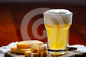 Glass of Belgian abbey brown beer with snack nuts in bar, pouring of beer