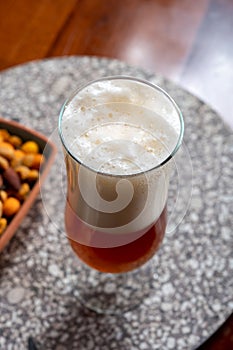 Glass of Belgian light blond beer made in abbey and bowl with party mix nuts