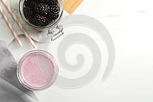 Glass of blackberry smoothie and berries on white table, flat lay. Space for text