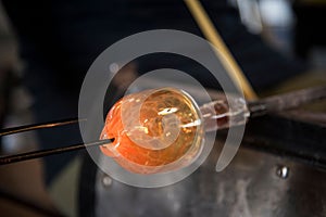 Glass blower making orange glass mold with high heat fire for shaping