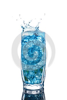 Glass of a blue alcoholic cocktail drink with ice and mint