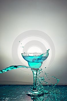 Glass with blue champagne or cocktail. Levitation