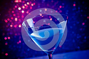 Glass blue cocktail on blue and violet tint light background