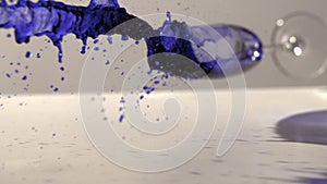 Glass of blue ink falling and spilling