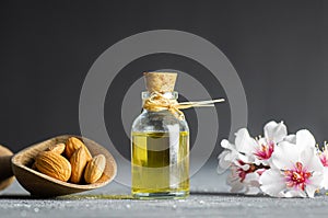 Glass bottle of Almond oil and almond nuts , almonds with almond tree flowers on table