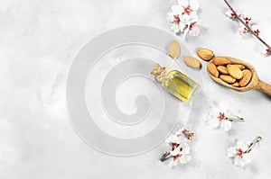 Glass bottle of Almond oil and almond nuts , almonds with almond tree flowers on table