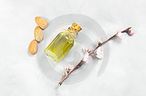 Glass bottle of Almond oil and almond nuts , almonds with almond tree flowers on table