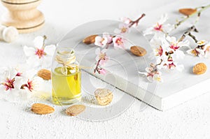 Glass bottle of Almond oil and almond nuts , almonds with almond tree flowers on table