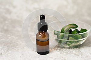 Glass bottle with aloe gel serum on gray background with copy space.