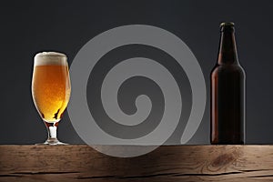 Glass and bottle of beer on dark grey background