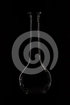 Glass bottle on a black background. Silhouette of bottle reflects light, promotional photo. Laconic minimalism, creative photo