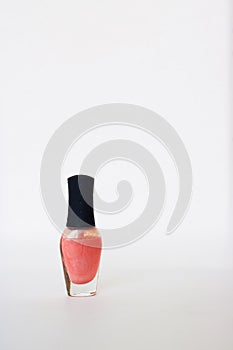 Glass bottle with black cap with pearl coral nail polish. Isolated object on white background. Nail polish. Beauty. manicure.