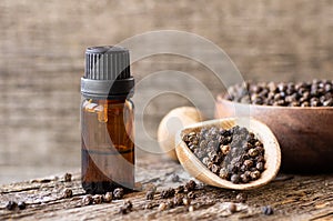 Glass Bottle of black pepper essential oil with peppercorns,