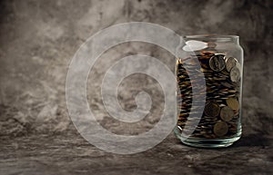 Glass bottle with a bottle full of coins to save for future business. Savings idea