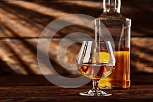 Glass and bottle of Cognac on wodden table.Wooden background