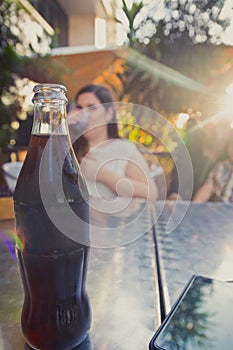 Glass bottle of cold cola soda on metal table