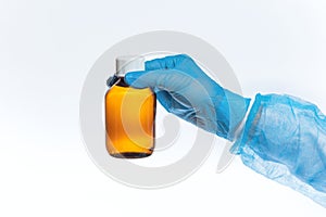 A glass bottle with cough syrup in the hands of a doctor, hands in medical gloves hold a bottle of antipyretic medicine on a white