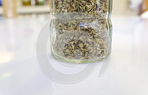 Glass bottle of dry oregano leaves