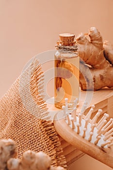 Glass bottle of essential ginger oil, ginger root on beige background. Healthy alternative living. Natural cosmetics