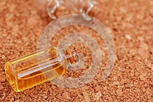 glass bottle of essential oil, essence, perfume on brown cork background.