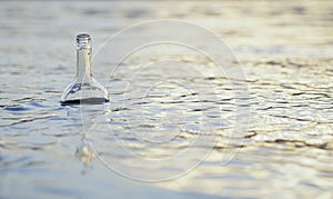 Glass bottle floats adrift in water