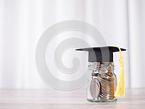 Glass bottle with graduation hat. The concept of saving money for education, student loan, scholarship, tuition fees in future