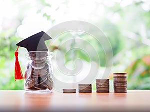 Glass bottle with graduation hat and stack of coins. The concept of saving money for education, student loan, scholarship, tuition