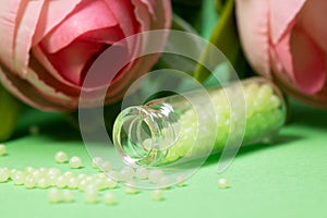 glass bottle with green granules and roses in the background. homeopathic remedies