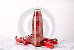 Glass bottle of hot chili sauce with peppers