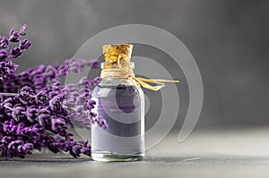 Glass bottle of Lavender essential oil with dried lavender flowers and seeds on white table